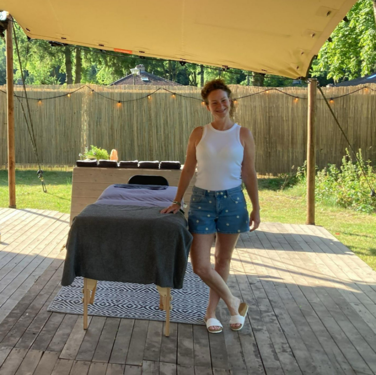 Marleen naast een massagetafel, klaar voor massages op locatie